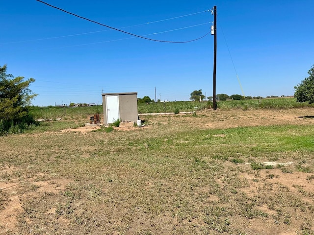 view of yard with a shed and a rural view