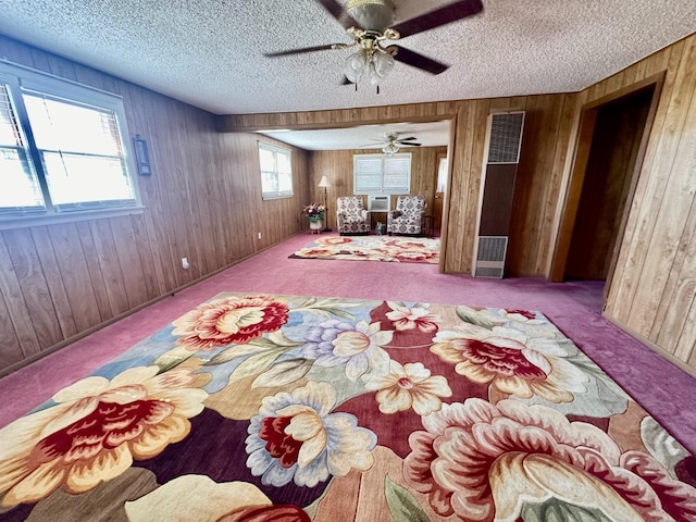 unfurnished bedroom featuring ceiling fan, wooden walls, light carpet, and a textured ceiling