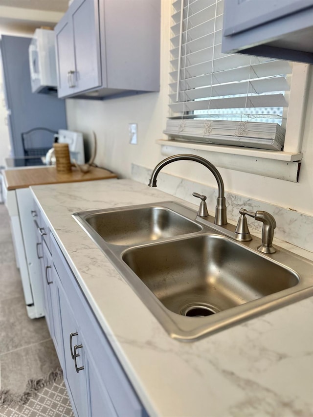 kitchen with light stone counters, range, sink, and light tile patterned floors