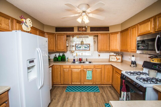 kitchen with sink, white appliances, dark wood-type flooring, ceiling fan, and tasteful backsplash