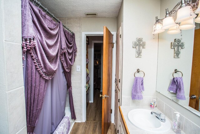 bathroom featuring hardwood / wood-style flooring, vanity, shower / tub combo, and a textured ceiling