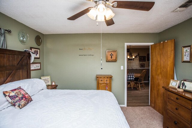 carpeted bedroom with ceiling fan and a textured ceiling