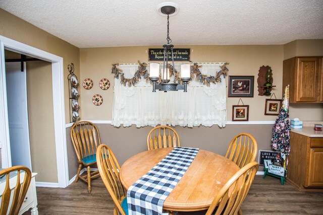 dining area featuring dark wood-type flooring, a textured ceiling, and a notable chandelier