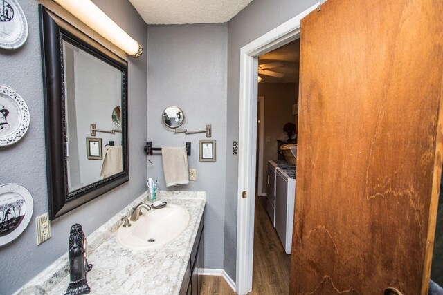 bathroom featuring vanity, separate washer and dryer, wood-type flooring, and a textured ceiling