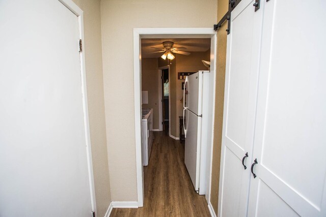 hall with washing machine and dryer, a barn door, and dark hardwood / wood-style flooring