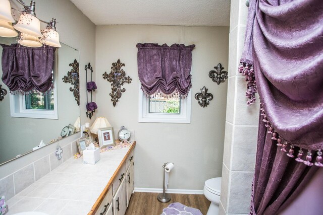 bathroom featuring vanity, hardwood / wood-style floors, a textured ceiling, and toilet