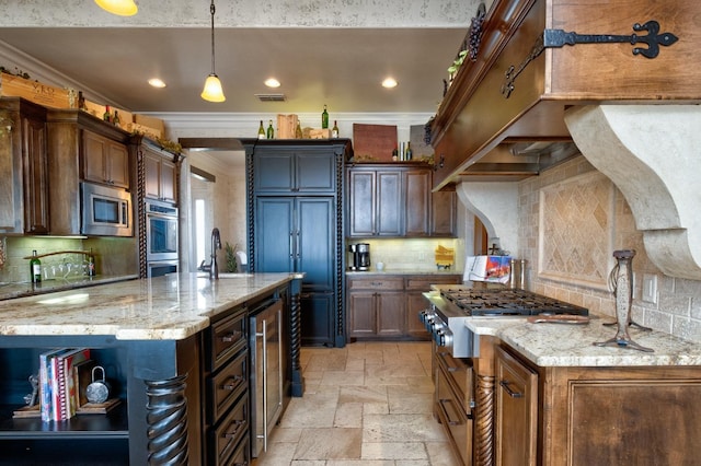 kitchen with stainless steel appliances, light stone counters, decorative light fixtures, beverage cooler, and a large island with sink