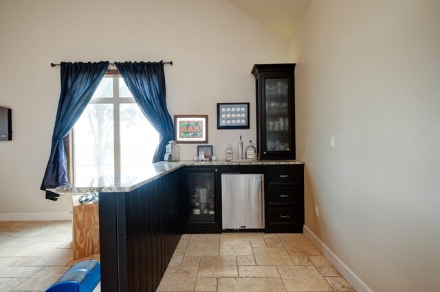 bar with fridge, lofted ceiling, and light stone counters