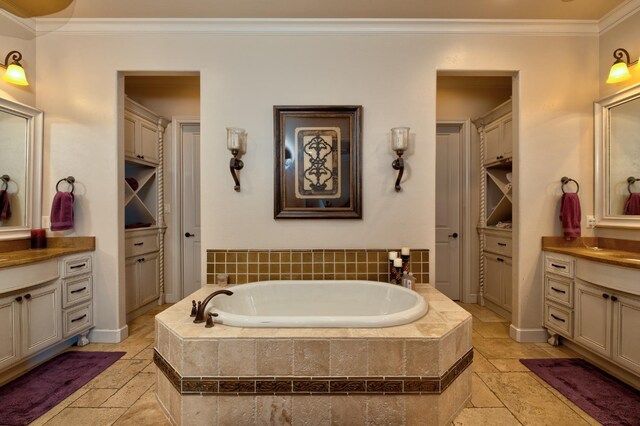 bathroom with crown molding, a relaxing tiled tub, and vanity