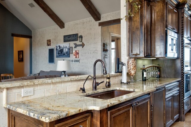 kitchen with light stone countertops, sink, and kitchen peninsula