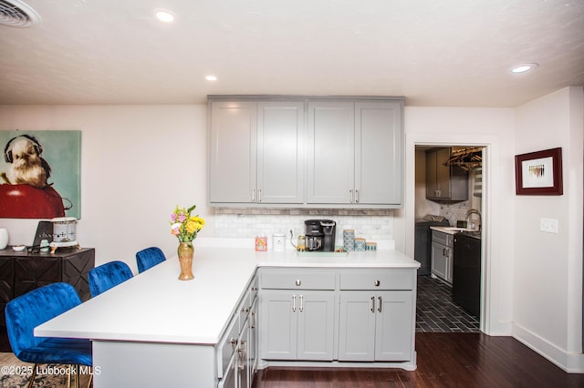 4609 10th St, Lubbock, TX 79416 - kitchen with light countertops, dark wood finished floors, tasteful backsplash, a peninsula, and a breakfast bar