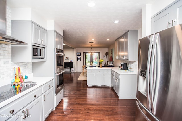 4609 10th St, Lubbock, TX 79416 - kitchen with appliances with stainless steel finishes, wall chimney exhaust hood, a peninsula, light countertops, and dark wood-style flooring