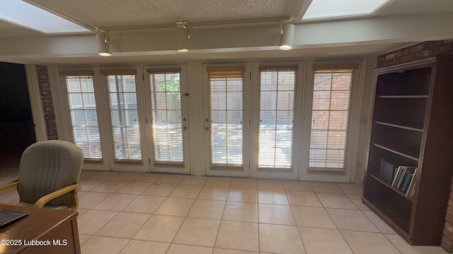3806 56th St, Lubbock, TX 79413 - doorway to outside with light tile patterned floors, a textured ceiling, and track lighting