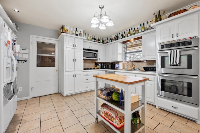 kitchen with light tile patterned floors, butcher block counters, open shelves, stainless steel appliances, and a notable chandelier