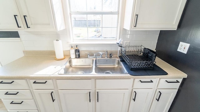 kitchen featuring white cabinetry, sink, and backsplash