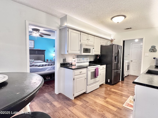 5623 87th St, Lubbock, TX 79424 - kitchen featuring white appliances, light wood-style flooring, a textured ceiling, separate washer and dryer, and dark countertops