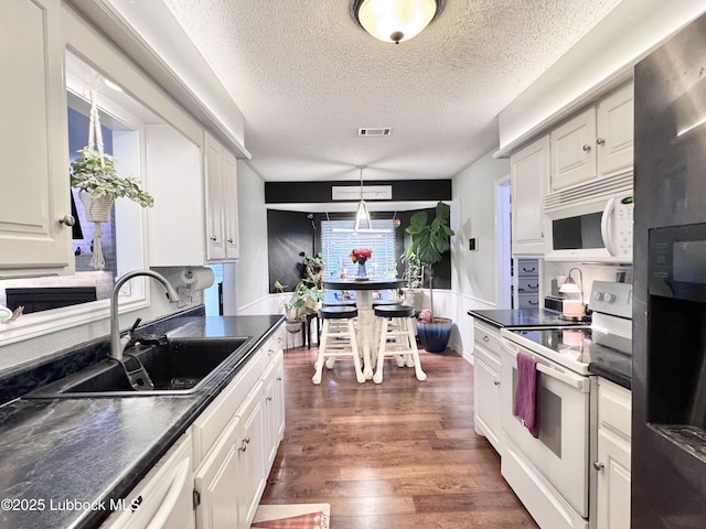 5623 87th St, Lubbock, TX 79424 - kitchen featuring white appliances, dark countertops, a textured ceiling, and white cabinetry