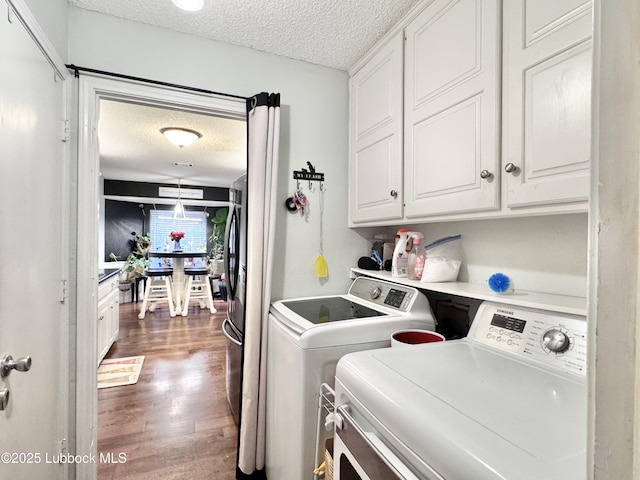 5623 87th St, Lubbock, TX 79424 - washroom featuring washing machine and clothes dryer, cabinet space, a textured ceiling, and wood finished floors