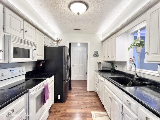5623 87th St, Lubbock, TX 79424 - kitchen with white appliances, a sink, a textured ceiling, dark countertops, and white cabinetry