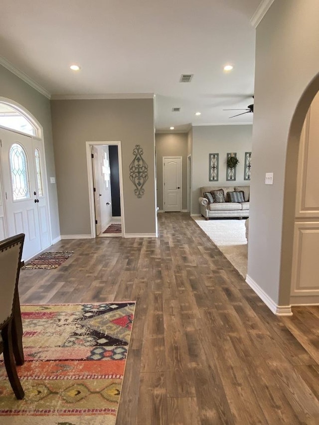 foyer featuring dark wood-type flooring, ceiling fan, and crown molding