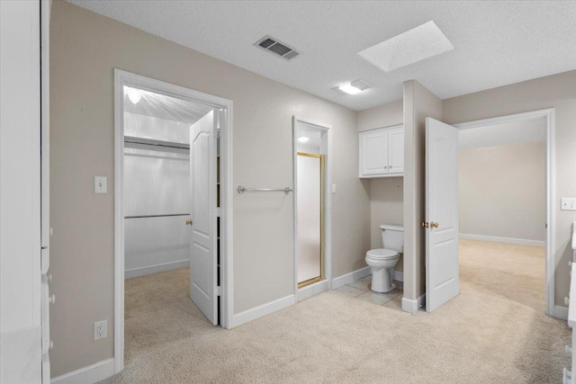 bathroom featuring an enclosed shower, toilet, a skylight, and a textured ceiling