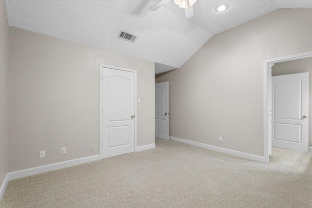 unfurnished bedroom with ceiling fan, lofted ceiling, light carpet, and a textured ceiling