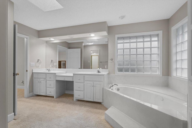 bathroom with a washtub, vanity, a skylight, and a textured ceiling