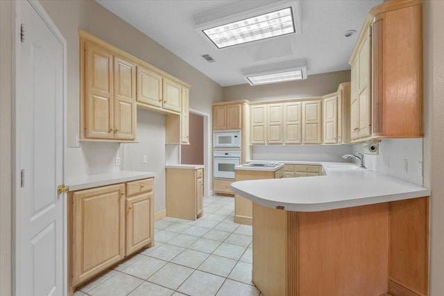 kitchen with sink, light brown cabinets, white appliances, and kitchen peninsula