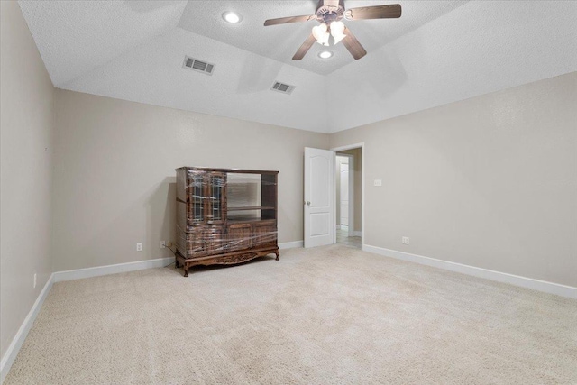 interior space featuring ceiling fan, light colored carpet, vaulted ceiling, and a textured ceiling