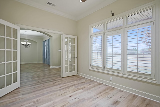 unfurnished room featuring french doors, crown molding, a chandelier, and light hardwood / wood-style flooring