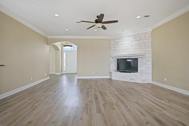 unfurnished living room featuring crown molding, a fireplace, light hardwood / wood-style floors, and ceiling fan