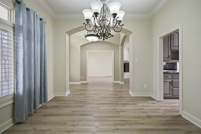 corridor featuring ornamental molding, light hardwood / wood-style floors, and a notable chandelier