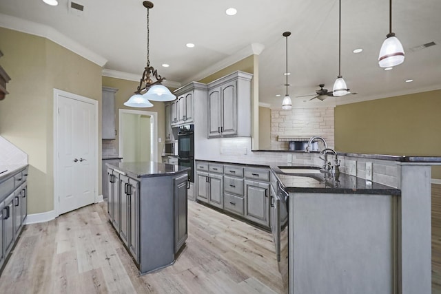 kitchen featuring gray cabinets, a kitchen island, sink, and pendant lighting