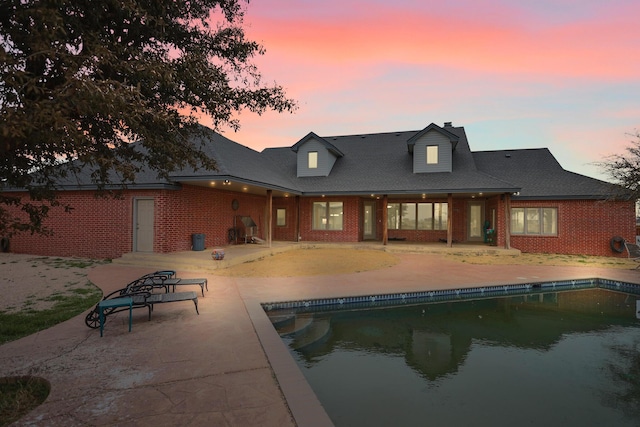 back house at dusk featuring a patio