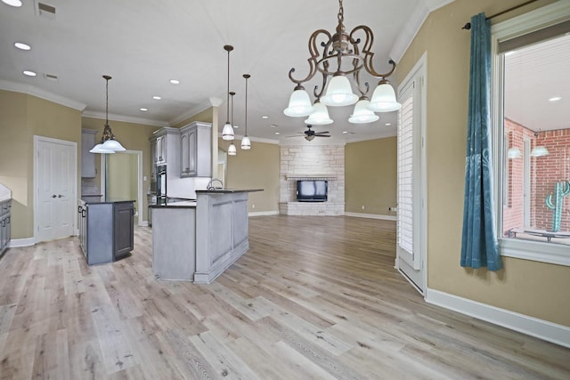 kitchen with crown molding, a large fireplace, decorative light fixtures, and gray cabinets