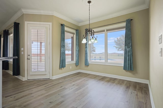 unfurnished dining area with ornamental molding, hardwood / wood-style floors, and a chandelier