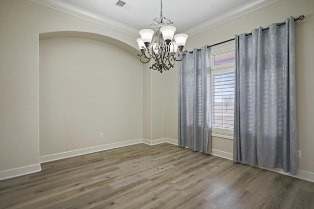 spare room with an inviting chandelier, wood-type flooring, and ornamental molding