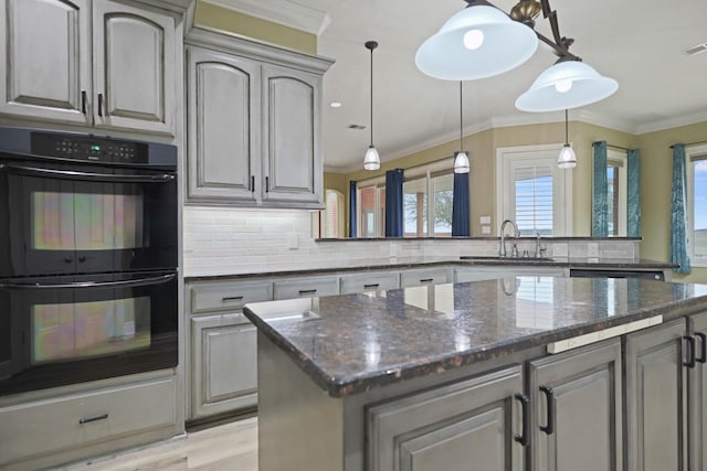 kitchen featuring double oven, sink, backsplash, dark stone counters, and crown molding