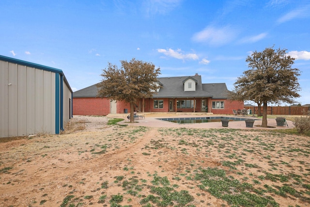 rear view of house featuring a fenced in pool and a patio area