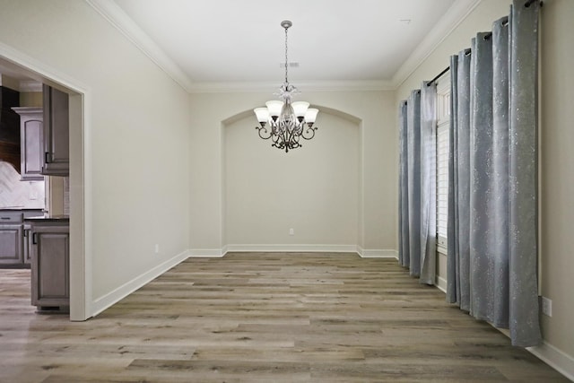 unfurnished dining area featuring an inviting chandelier, hardwood / wood-style flooring, and ornamental molding