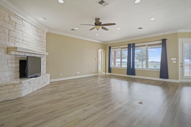 unfurnished living room featuring crown molding, a large fireplace, ceiling fan, and light hardwood / wood-style floors