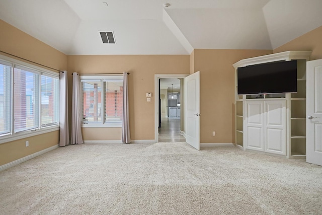 unfurnished bedroom featuring light carpet, lofted ceiling, and a closet