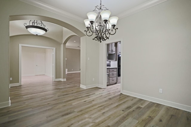 unfurnished dining area featuring hardwood / wood-style flooring, ornamental molding, and an inviting chandelier