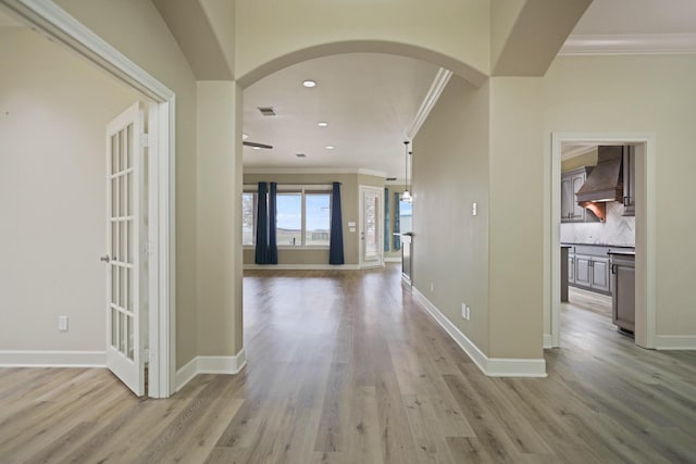 hallway featuring crown molding and light hardwood / wood-style flooring