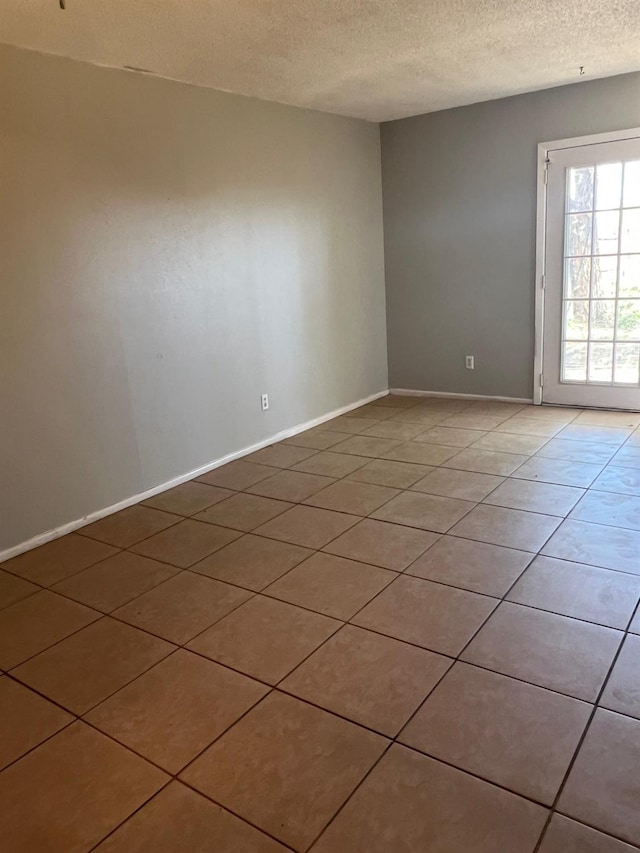 tiled empty room with a textured ceiling