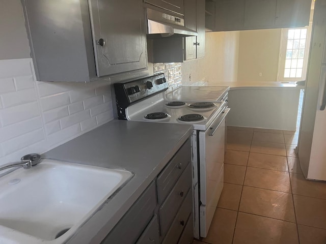 kitchen with white range with electric stovetop, sink, gray cabinetry, decorative backsplash, and light tile patterned floors