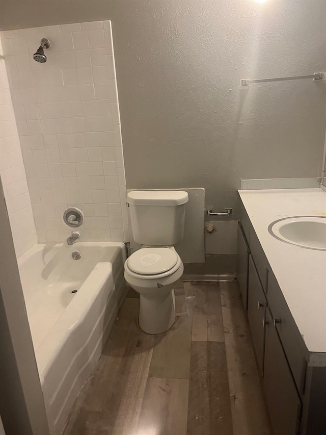 full bathroom featuring tiled shower / bath combo, vanity, hardwood / wood-style flooring, and toilet