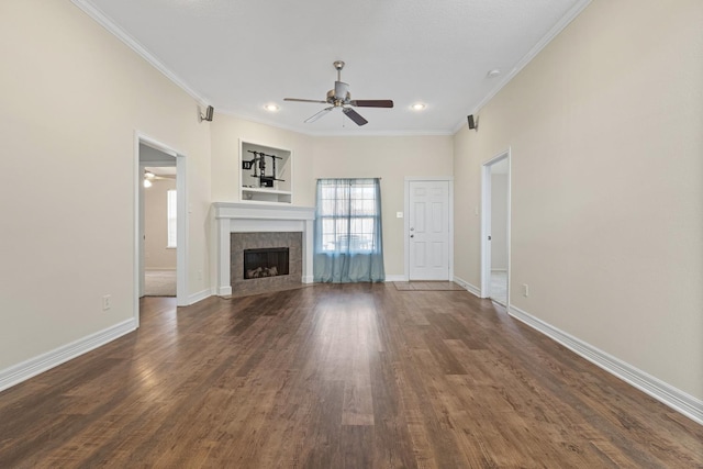 unfurnished living room with dark hardwood / wood-style flooring, ornamental molding, a tile fireplace, and ceiling fan