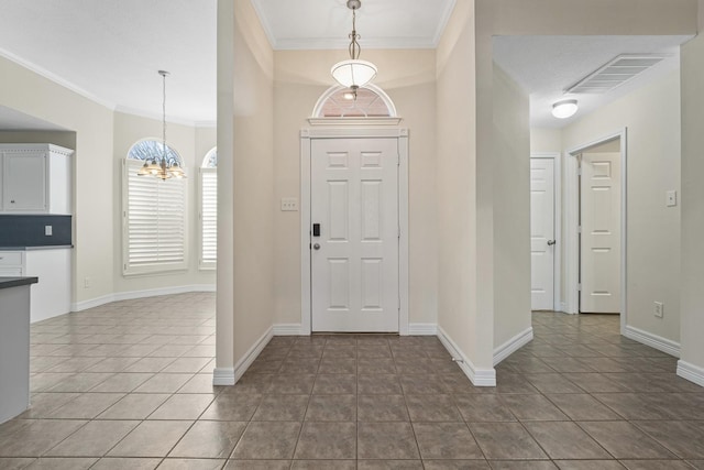 tiled entrance foyer with crown molding and a chandelier