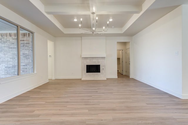 unfurnished living room with beam ceiling, coffered ceiling, light wood-type flooring, and an inviting chandelier